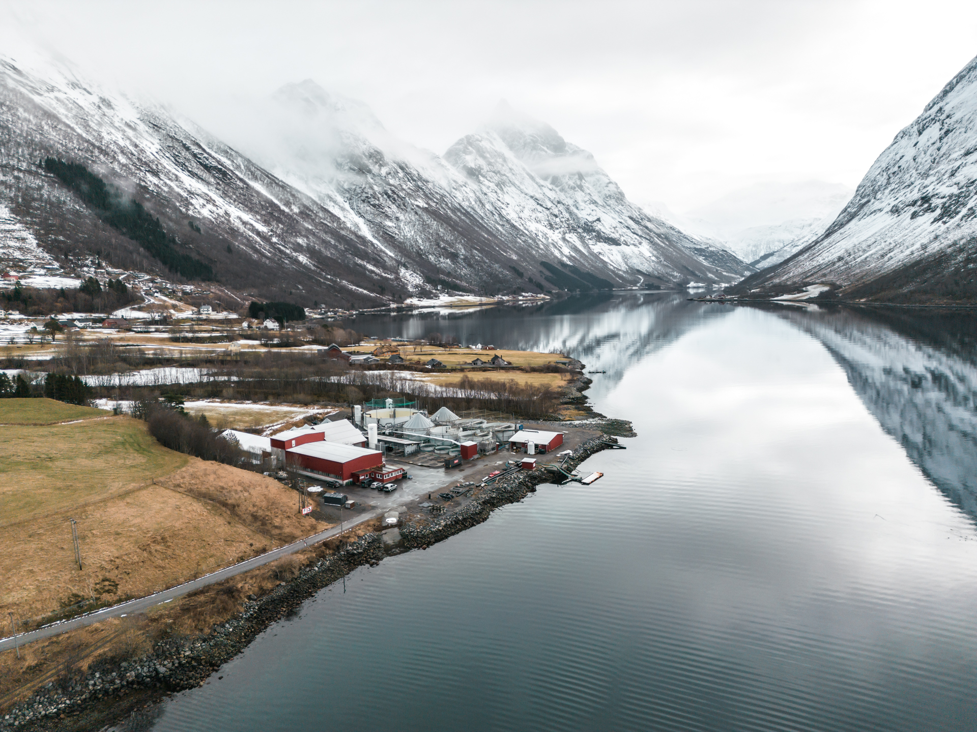 Foto av fiskeoppdrett på fjorden sett fra lufta