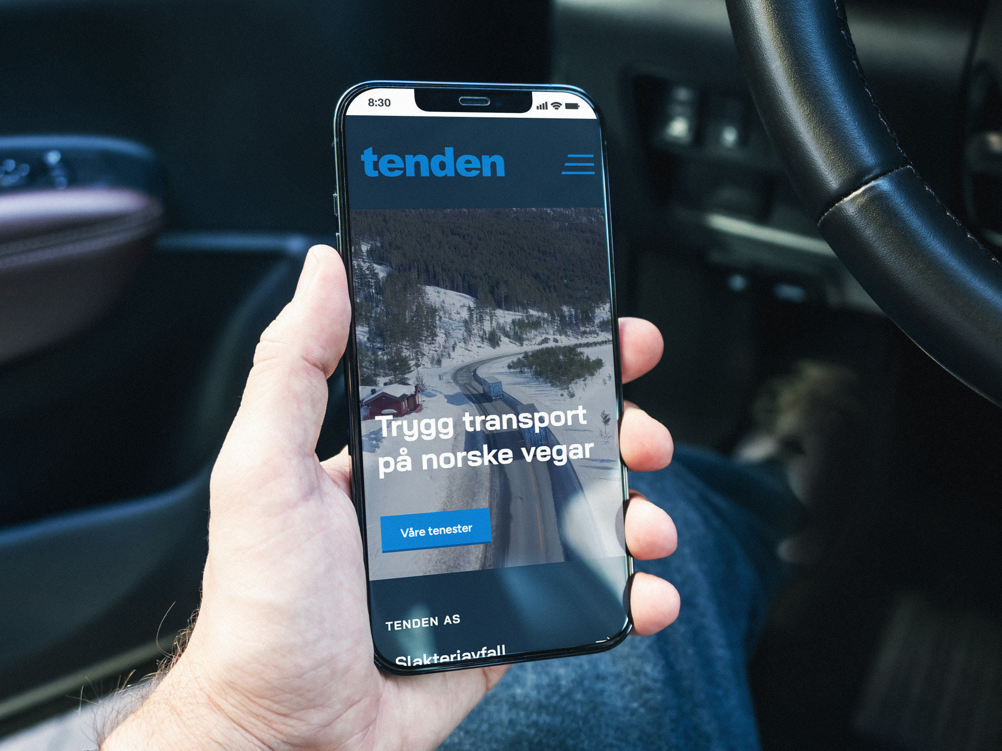 En hånd holder en mobiltelefon hvor tenden sin nye nettside vises på skjermen.